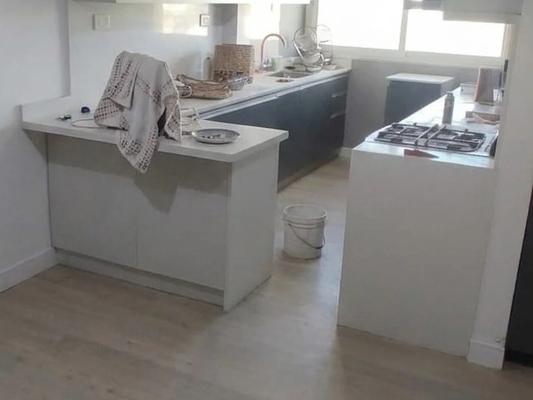 Antes: La cocina del mismo departamento. El piso pálido no es su color: es el polvo de obra. Después del lavado vuelve el tono real de la madera.