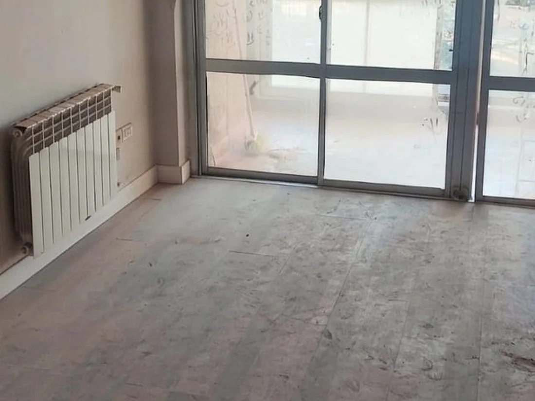 Antes: Living de un departamento en Córdoba: polvo fino de obra sobre el piso y en el ventanal.