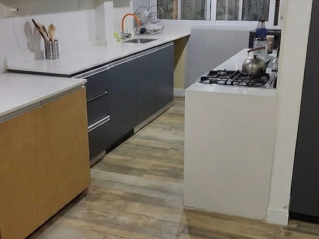 Después: La cocina del mismo departamento. El piso pálido no es su color: es el polvo de obra. Después del lavado vuelve el tono real de la madera.