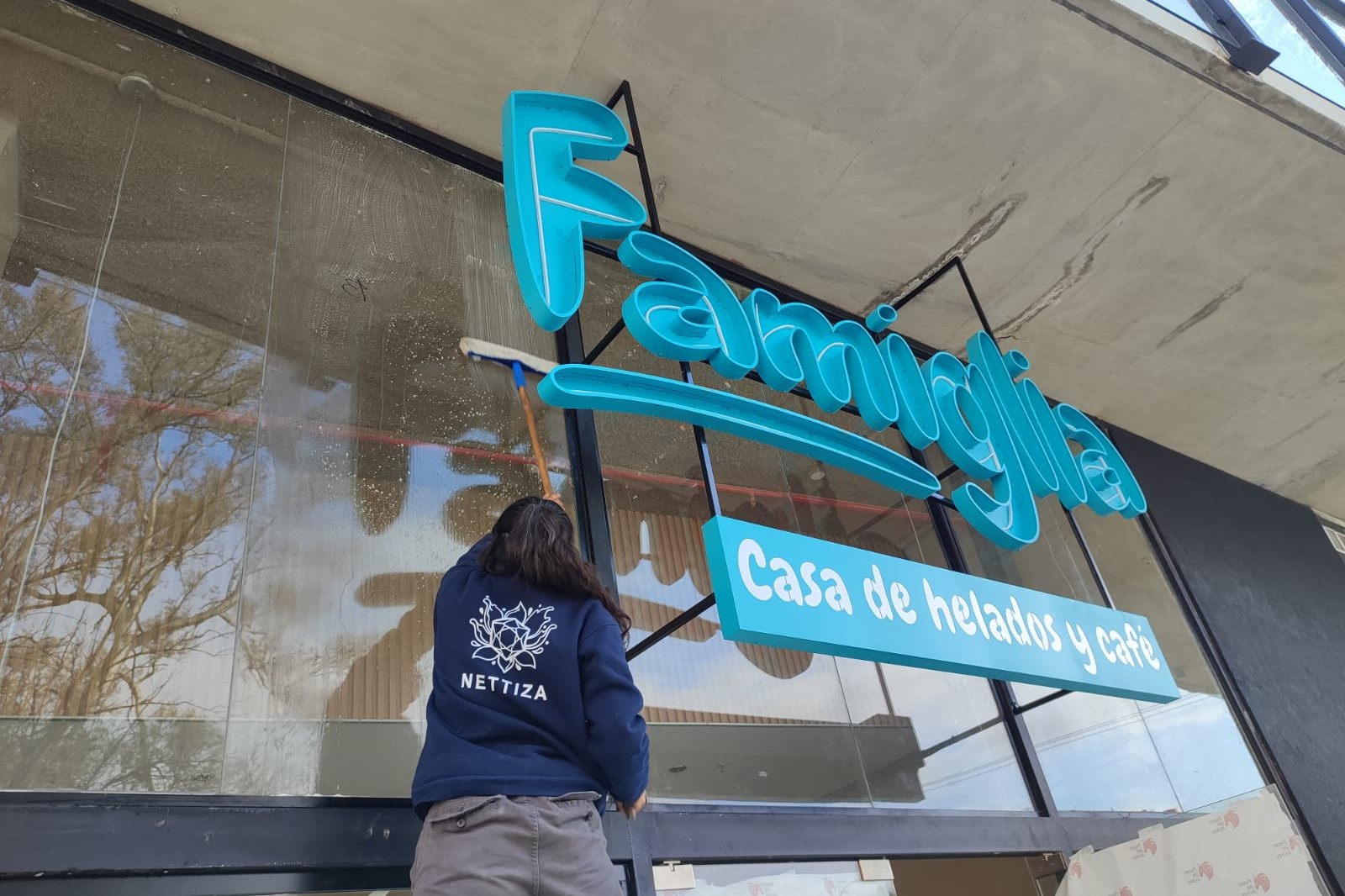 Operaria de NETTIZA limpiando el ventanal de Famiglia, casa de helados y café en Córdoba