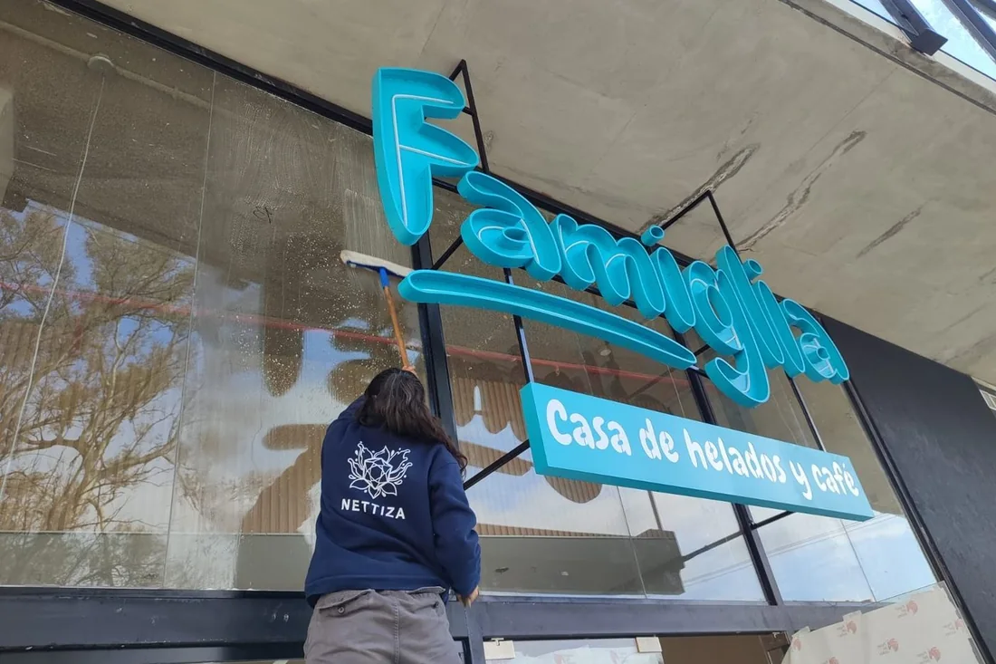 Operaria de NETTIZA limpiando el ventanal de Famiglia, casa de helados y café en Córdoba